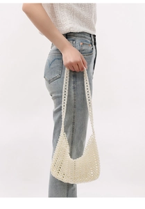 Détail d'un sac hobo en perles blanches tissées à la main porté à l'épaule par un mannequin