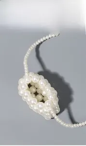 Detail of elegant handmade white pearl woven crossbody bag with long strap and small pouch
