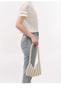 Detailed view of the handcrafted ivory pearl woven handbag for elegant styling