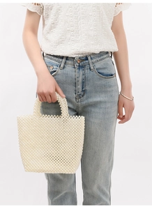 Detailed view of handmade white pearl woven handbag showing intricate beaded texture