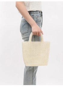 Detail shot of a handmade white pearl woven tote bag with elegant beaded top handles