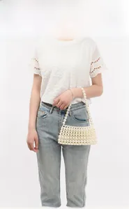 Detail shot of a handmade pearl beaded shoulder bag worn by a model in a studio setting