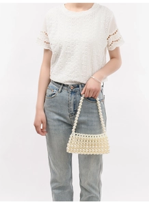 Macro detail of the hand-woven pearl shoulder bag featuring glossy cream round beads