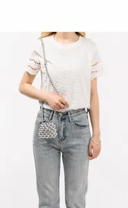 Silver beaded crossbody bag worn by model with white lace top and denim jeans