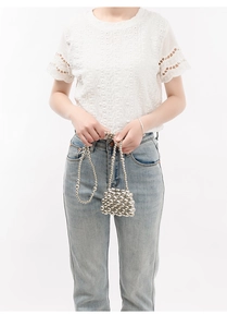 Detailed view of silver metallic beaded crossbody bag worn with a white dress
