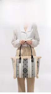 Detail of woven canvas tote bag with bohemian tassels and black leather handle