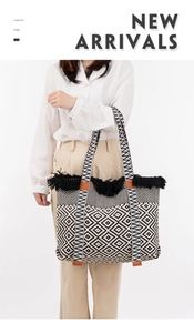 Macro detail of large woven tote bag featuring black and white geometric patterns and tassels