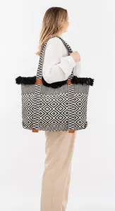 Detail of woven tote bag featuring black fringe trim and geometric diamond pattern