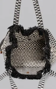 Macro shot of large canvas tote bag showing spacious interior and black fringe details