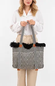 Detail view of woven tote bag with black and white geometric patterns and tassel edges