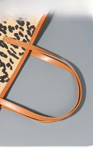 Detail showing leopard print canvas texture with brown PU leather strap and gold rivets