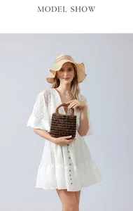 Close-up of handmade brown beaded woven handbag styled with a white lace summer dress