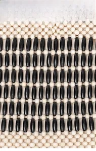 Dettaglio del motivo di perle di legno intrecciate con fusi neri e sfere bianche