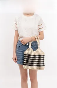 Dettaglio di una borsa a mano intrecciata a mano con perle bicolore per le vacanze al mare