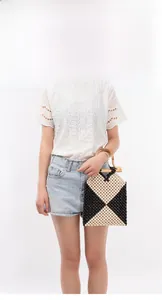 Detail view of contrast wood bead handbag with geometric patterns and bamboo handle