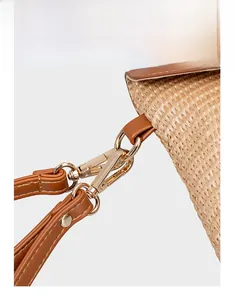 Detail of reinforced gold-plated metal clasp and premium brown leather strap on straw bag