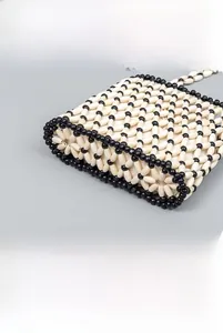 Macro view showing the intricate black and white hand-woven wooden bead texture on the bag