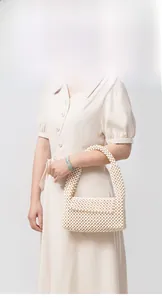 Detailed view of cream-white hand-woven wooden bead bag with a curved top handle