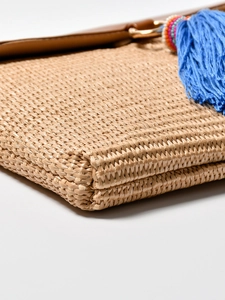 Handwoven straw beach clutch with blue tassels and colorful beads for summer seaside vacation
