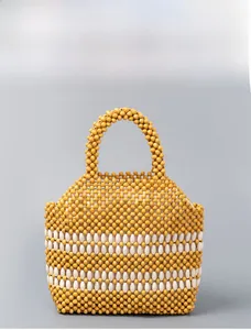 Close-up of handmade yellow beaded handbag with decorative white oblong bead accents