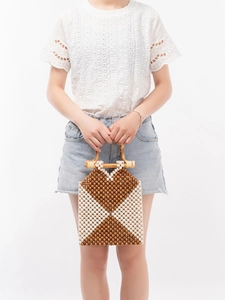 Handmade woven beaded handbag with brown geometric patterns and bamboo handles for beach vacations