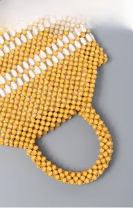 Detail of bohemian handmade woven bag showing smooth yellow and white wooden beads texture