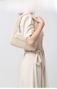 Detail view of a cream beaded handbag with handcrafted wooden beads on a model