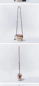 Detail of raffia woven crossbody bag with geometric patterns and orange floral accents