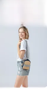 Detail of hand-woven straw crossbody bag featuring navy faux leather trim and jacquard strap