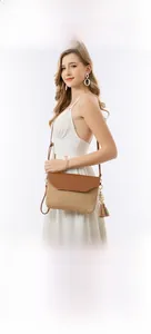 Detail view of woven straw crossbody bag featuring colorful tassel charms and brown leather flap