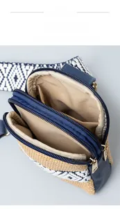 Detail view of woven shoulder bag featuring triple zipper compartments and patterned strap