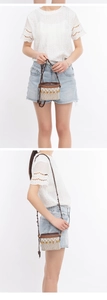Detail of hand-woven raffia bucket bag with geometric patterns and wooden bead drawstring