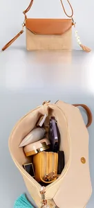 Detail of straw shoulder bag with leather flap showing interior space and tassel decor