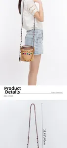 Detail view of woven straw bucket bag showing size dimensions and colorful pom-poms