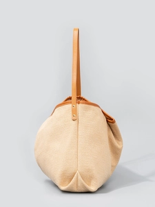 Large woven tote bag with brown leather handles and gold studs for beach and travel