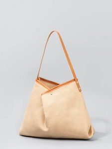 Minimalist straw tote bag with brown leather trim and unique asymmetric folding design