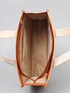Beige straw woven tote bag with brown leather trim and spacious interior storage