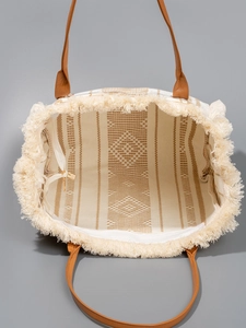 Ethnic woven canvas tote bag with bohemian tassels and leather handles in a top-view shot