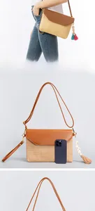 Detail view of straw woven crossbody bag with leather flap, shells, and tassels decoration