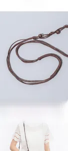 Detail of hand-woven brown cotton strap with vintage wooden beads on straw bucket bag