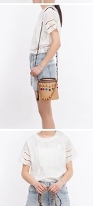 Detail of hand-woven straw bucket bag featuring colorful pom-poms and beaded charms