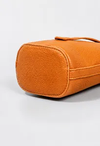 Detalle del bolso tipo cubo en cuero PU naranja mostrando costuras finas y grano litchi