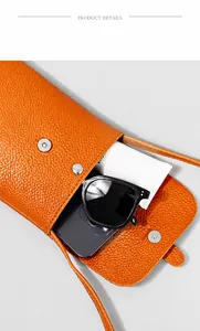 Innenansicht der orangefarbenen Handy-Umhängetasche aus Leder mit Brille und Smartphone