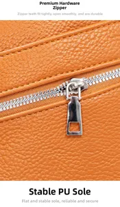 Detail van oranje PU-leer met lychee-korrel en zilveren metalen rits op de crossbody tas