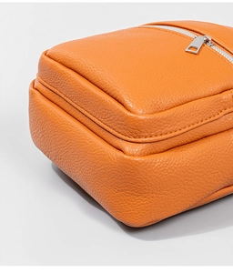 Detailed macro view of orange lychee textured PU leather with fine stitching and silver zipper