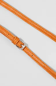 Detail von orangefarbenem Lederriemen mit Litschi-Struktur und silberner verstellbarer Schnalle