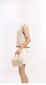 Detail of hollow woven texture and rounded handle on a beige beaded handbag