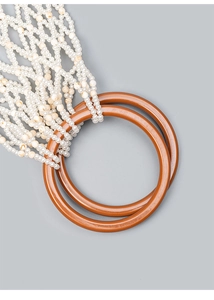 Detailed macro view of woven faux pearl beads and polished resin ring handles on a handbag