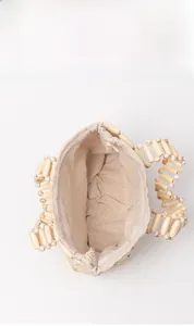 Detail view of woven wood bead handbag with beige linen lining showing internal capacity
