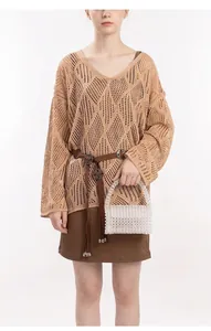 Dettaglio di una borsa fatta a mano in perline abbinata a un elegante maglione kaki traforato